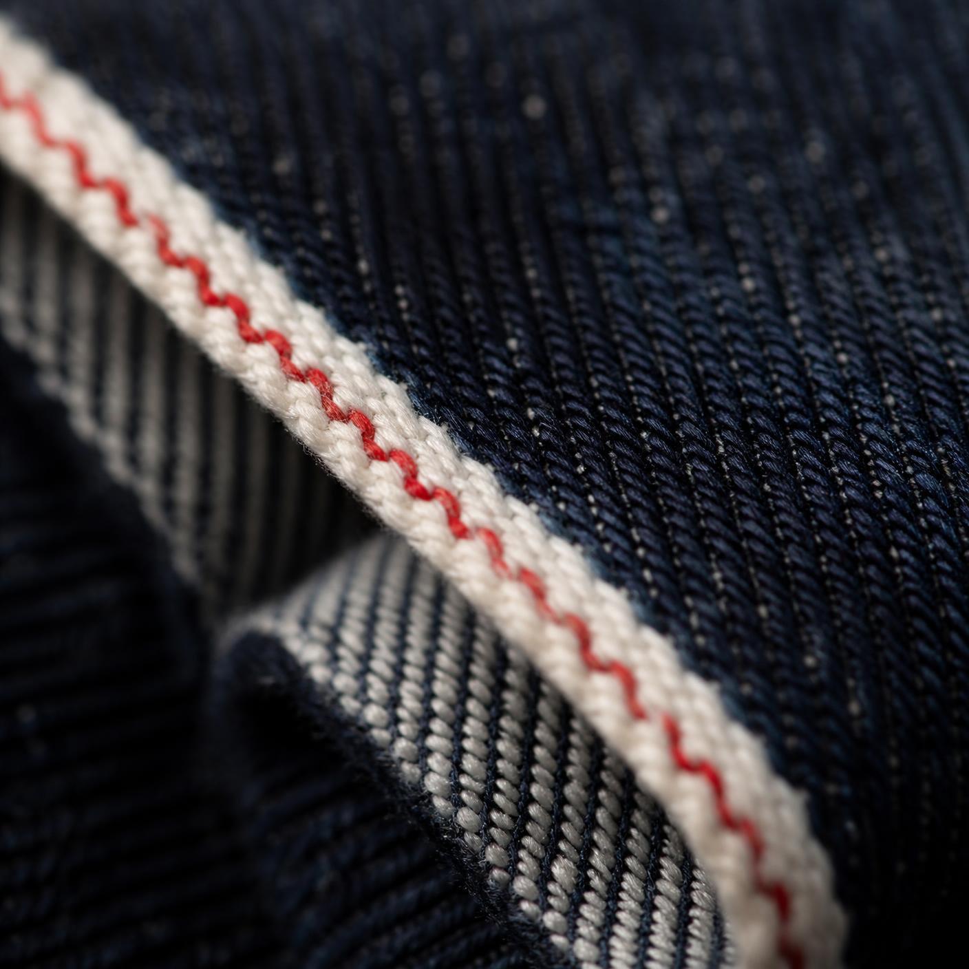 Macro photograph of Japanese selvage denim showing the red-line self-finished edge.